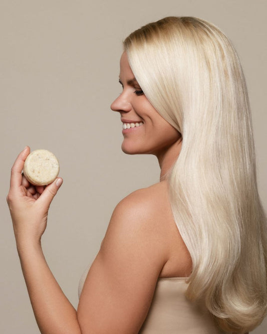 Shampoing Solide Tilleul et Bouleau Nordique tenu par une femme souriante avec de très beaux cheveux blonds